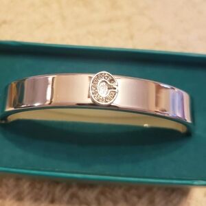 PRETTY KOHLS SILVER TONE BANGLE BRACELET WITH FAUX DIAMOND "C". OPENS FOR EASE.